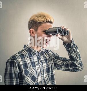 Junger Mann, Blick durch ein Fernglas Stockfoto