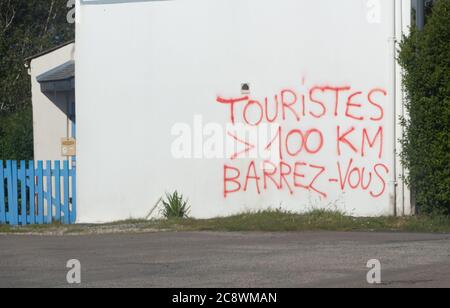 Esquibien – Frankreich, 14. Mai 2020 : Graffiti Touristen mehr als 100km gehen weg geschrieben in französischer Sprache an der Wand eines Hauses nach der Sperre für Stockfoto