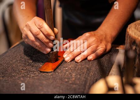 Nahaufnahme der Hände einer Lederhandfrau, die einen handgefertigten Gürtel herstellt Stockfoto
