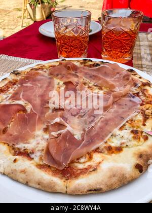 Pizza mit Prosciutto und Gläser aperol Spritz auf dem Tisch Stockfoto