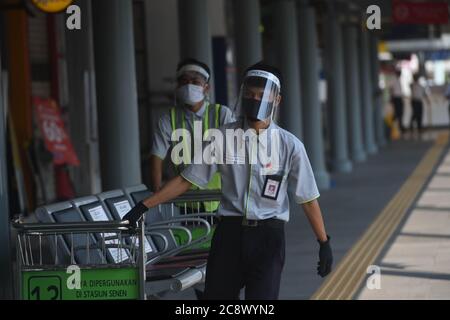 Jakarta, Indonesien. Juli 2020. Mitarbeiter mit Gesichtsschilden und Masken arbeiten am Bahnhof Pasar Senen in Jakarta, Indonesien, 27. Juli 2020. Die COVID-19 Fälle in Indonesien stiegen innerhalb eines Tages um 1,525 auf 100,303, wobei die Zahl der Todesopfer um 57 auf 4,838 stieg, teilte das Gesundheitsministerium am Montag mit. Das Virus hat sich in allen 34 Provinzen des Landes verbreitet. Kredit: Zulkarnain/Xinhua/Alamy Live Nachrichten Stockfoto