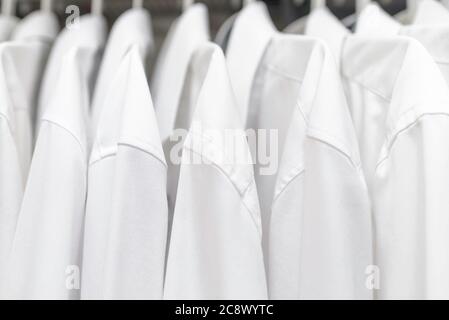 Weiße Herrenhemden an Kleiderbügeln im Kleiderschrank Stockfoto