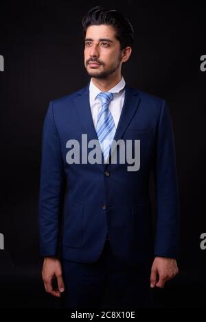 Junge gut aussehende bärtige persische Geschäftsmann vor schwarzem Hintergrund Stockfoto