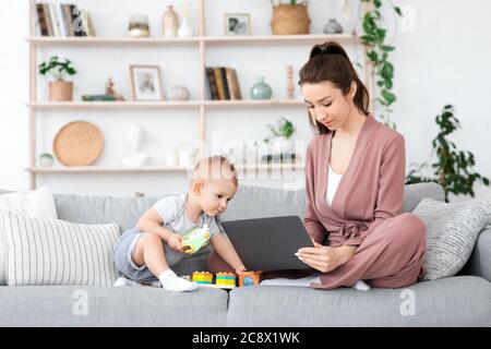 Online-Kurse Für Mütter. Junge Frau Studieren Mit Laptop Neben Baby Stockfoto