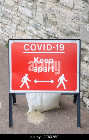 Temporäres rotes Metallzeichen, das soziale Distanzierung berät, liest „Covid-19 halten auseinander“, während der Coronavirus-Pandemie. Dorchester Stadtzentrum, England, Großbritannien. Stockfoto