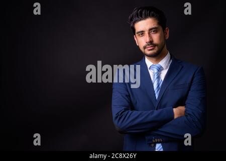 Junge gut aussehende bärtige persische Geschäftsmann vor schwarzem Hintergrund Stockfoto