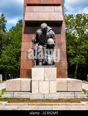 Bronze kniende Soldatenskulptur vor abstrakter Granitfahne am Sowjetischen Kriegsdenkmal im Treptow Park, Berlin, Deutschland Stockfoto