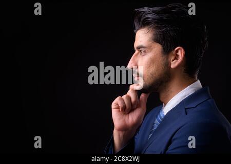 Junge gut aussehende bärtige persische Geschäftsmann vor schwarzem Hintergrund Stockfoto