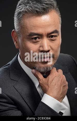 Berühren Sie mit den Fingern den Bart des Geschäfts bei Männern mittleren Alters Stockfoto