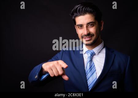 Junge gut aussehende bärtige persische Geschäftsmann vor schwarzem Hintergrund Stockfoto