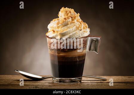 Tasse Kaffee mit Schlagsahne, Schokoladenschaum und Haselnusskorn. Stockfoto