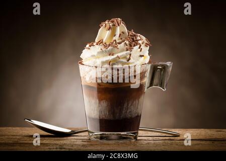 Tasse Kaffee mit Schlagsahne, Milchschaum und Schokoladenstückchen. Stockfoto