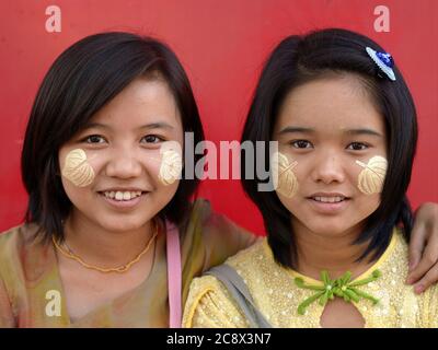 Zwei hübsche burmesische Teenager-Mädchen mit blattförmigen natürlichen Thanaka Gesicht Kosmetik auf ihre Wangen gemalt Lächeln für die Kamera. Stockfoto