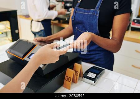 Hände des Kunden, der Kreditkarte an die Kasse gibt, wenn er im Café für die Bestellung bezahlt Stockfoto