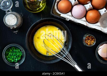 Eier in einer Schüssel schlagen, und Zutaten für die Herstellung eines Omelettes mit grünen Zwiebeln. Stockfoto