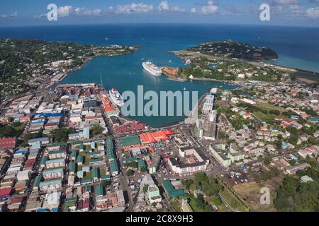 Castries, Hafen und Hauptstadt von St. Lucia in der Karibik, Westindien. Luftaufnahme von Straßen, Gebäuden und zwei Kreuzfahrtschiffen mit Flughafen oben rechts Stockfoto