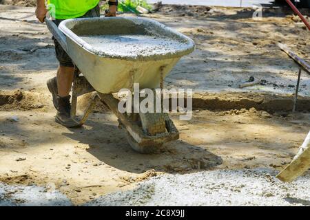 Bauarbeiter schieben Schubkarre mit Beton beim Bau eines Ingenieurs auf Bau Stockfoto