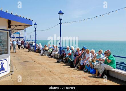 Gruppe von hauptsächlich älteren Damen, die in der Sonne auf dem Pier in Eastbourne, East Suusex, England sitzen Stockfoto