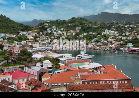 Mit Blick auf den Hafen und die Uferpromenade von St. George's mit Luxusjacht und Häusern an den Hängen dahinter, Grenada Insel, die Karibik Stockfoto