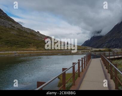 Weg zum Aussichtspunkt Plattform auf Trollstigen oder Trolls Pfad mit Holzhütten Hütte am Massiv Trolltindene im Romsdal Tal, Norwegen. Bewölkt Stockfoto