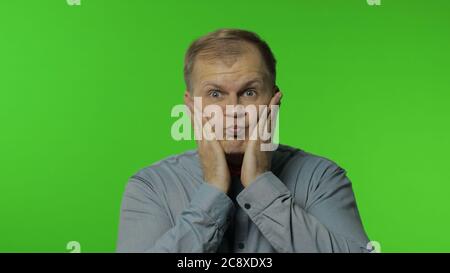 Überrascht lustig komisch Mann dummes Gesicht mit aufgeblasen die Wangen und mit schockierten dummen idiotischen Ausdruck, Grimasse, herumtäuschen. Portrait von Kerl posiert auf Chroma-Schlüssel Hintergrund Stockfoto