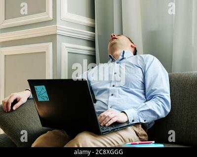 Müde Mann mit chronischem ermüdungserscheinungserscheinungen cfs schläft mit Laptop. Stockfoto