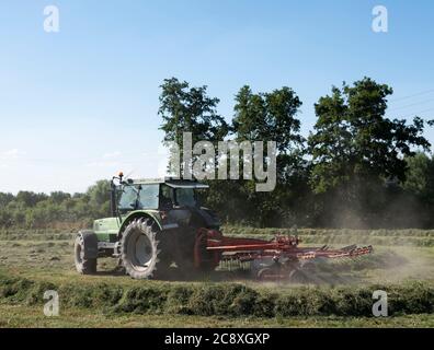 Traktor mit Rasenwender in französischer Landschaft mit Bäumen Stockfoto