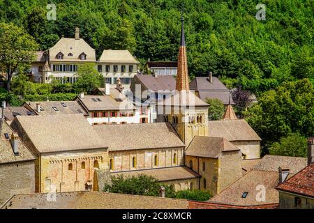 Panoramablick auf die romanische Stiftskirche in der mittelalterlichen Stadt Romainmotier, Kanton Waadt, Schweiz. Stockfoto