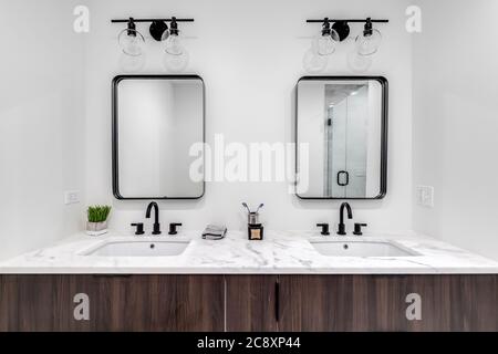 Ein wunderschönes, modernes Badezimmer mit einem Holzwaschtisch, einer weißen Marmorablage und einer individuell gekachelten Duschkabine. Stockfoto