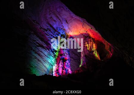 Beleuchtet mit den bunten Lichtern Stalaktiten und Stalagmiten in atemberaubenden Innenraum der schönen Huanglong Yellow Dragon Cave auch Th Stockfoto