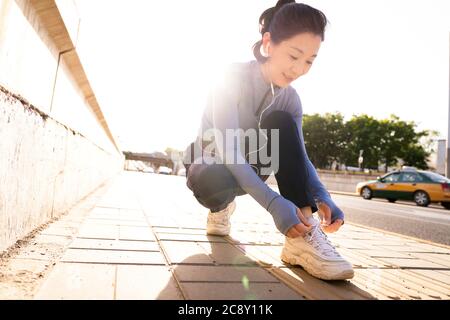 Die Frau mittleren Alters neben der Straße, um meinen Schuh zu binden Stockfoto