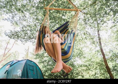 Eine junge Frau, die sich in einer Hängematte entspannt. Mädchen in den Wäldern ruhen, Camping in einer Hängematte. Gesunde Lebensweise im Wald. Stockfoto