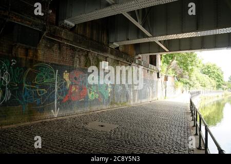 Metallbalken einer alten Eisenbahnbrücke über den Severn Fluss mit gepflasterten Weg am Fluss und Graffiti. Stockfoto