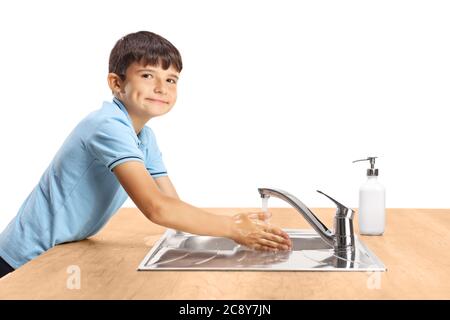 Junge, die sich in einem Waschbecken die Hände wusch und lächelte die Kamera isoliert auf weißem Hintergrund an Stockfoto
