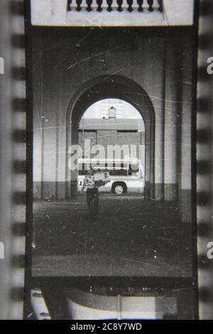 Feine Schwarz-Weiß-Fotografie aus den 1970er Jahren von einem Mann auf der Straße, der unter einem Bogen vorbeigeht. Stockfoto