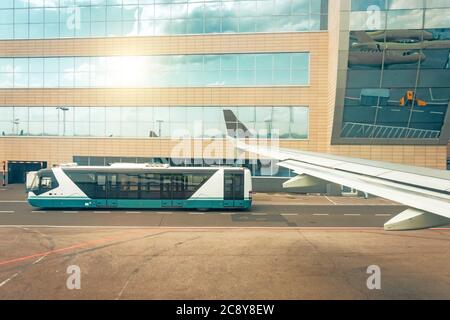 Blick von einem Flugzeugflügel auf einen vorbeifahrenden Personenbus im Hintergrund des Terminals Stockfoto