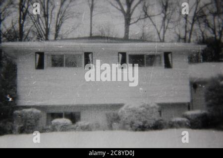 Feine 70er Jahre Vintage Schwarz-Weiß-Fotografie eines gemeinsamen Vorstadt Split-Level-Familie zu Hause im Winter mit Schnee bedeckt. Stockfoto