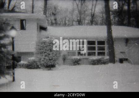 Feine 70er Jahre Vintage Schwarz-Weiß-Fotografie eines gemeinsamen Vorstadt Split-Level-Familie zu Hause im Winter mit Schnee bedeckt. Stockfoto