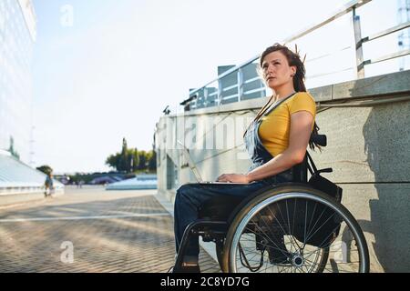 Gut aussehende Mädchen in T-Shirt und insgesamt Beschäftigung finden, Nahaufnahme Foto. Copy space.verschwommen Hintergrund. Legitimierte Arbeit von zu Hause. Mädchen denken ein Stockfoto