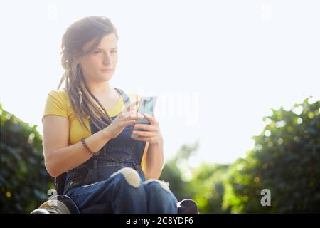 Nachdenklich nachdenklich nettes Mädchen in gelben T-Shirt und insgesamt hält ihr Handy in den Händen Blick auf die Kamera, Frau, die einen Anruf. Copy sp Stockfoto