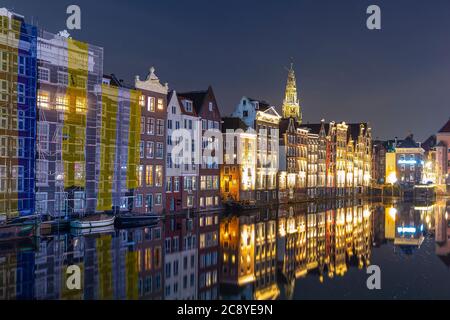 Amsterdam Damrak traditionelle holländische Architektur bei Nacht. Tour Kreuzfahrtschiffe im Vordergrund. Stockfoto