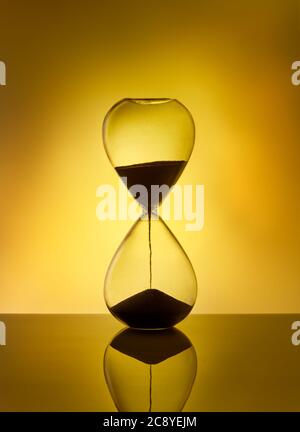 Hourglass als Zeitverlaufkonzept für Deadline, läuft aus der Zeit. Sandglas auf gelbem Hintergrund. Konzept der Dringlichkeit. Stockfoto