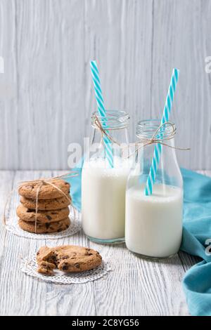 Flaschen Milch und Schokoladenkekse auf Holzhintergrund Stockfoto