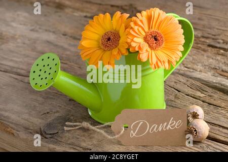 Blumen mit Pappschild und Schriftzug (deutsch für Danke) Stockfoto