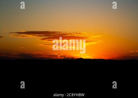 Sonnenaufgang mit Silhouetten von Windkraftanlagen am Horizont Stockfoto