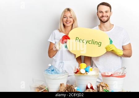 Positiv lächelnder junger Mann und Frau, die Menschen raten, Abfall, Müll, Nahaufnahme Porträt, Studioaufnahme, aufhören, Schaden für unseren Planeten zu tun, volunte Stockfoto