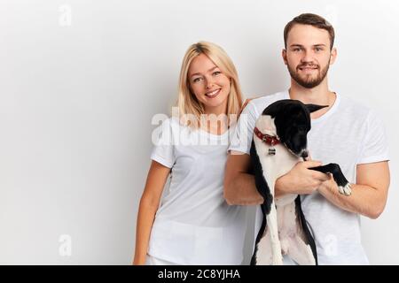 Gut aussehende junge Mann und Frau in stilvollen weißen T-Shirts Spaß mit einem Hund. Nahaufnahme Porträt. studio shot.love, Freundschaft Stockfoto