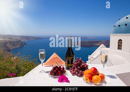 Wein und Obst für zwei auf dem Hintergrund des Meeres und der Insel Santorini. Stockfoto