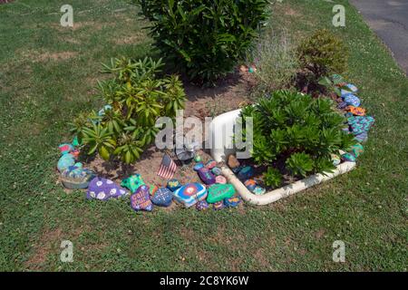 Ein ungewöhnliches Vorgarten-Display mit einer Küchenspüle und handbemalten Steinen. In Flushing, Queens, New York City. Stockfoto