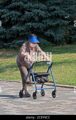 Eine ältere asiatische amerikanische Frauen (wahrscheinlich Chinesen) auf einem Übungsweg, während sie sich auf ihren Spaziergänger lehnt. In Flushing, Queens, New York City. Stockfoto